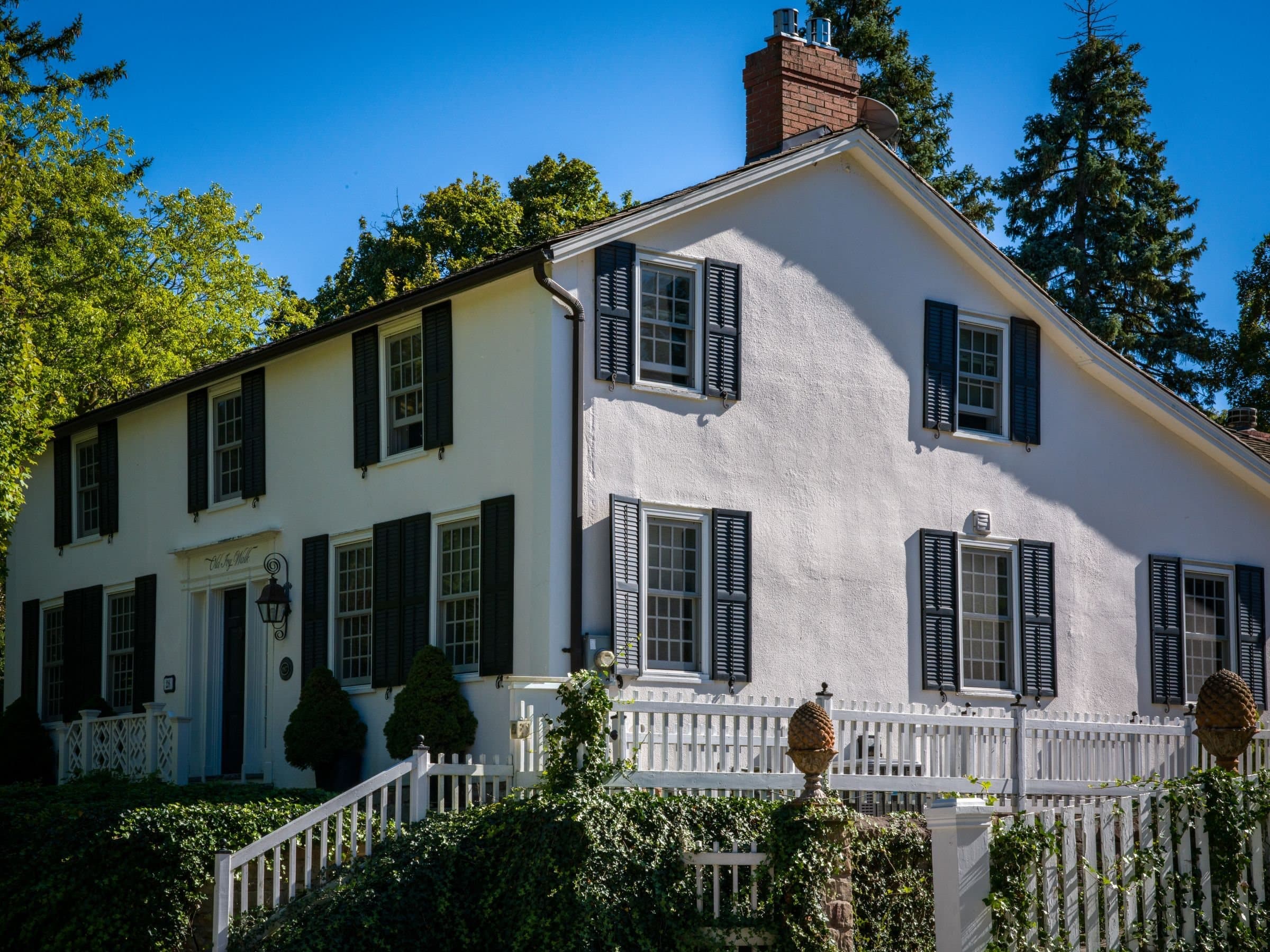 Greenwich, CT: a white colonial house with black shutters behind a white picket fence
